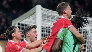 Wrexham players mob keeper Arthur Okonkwo after his penalty heroics