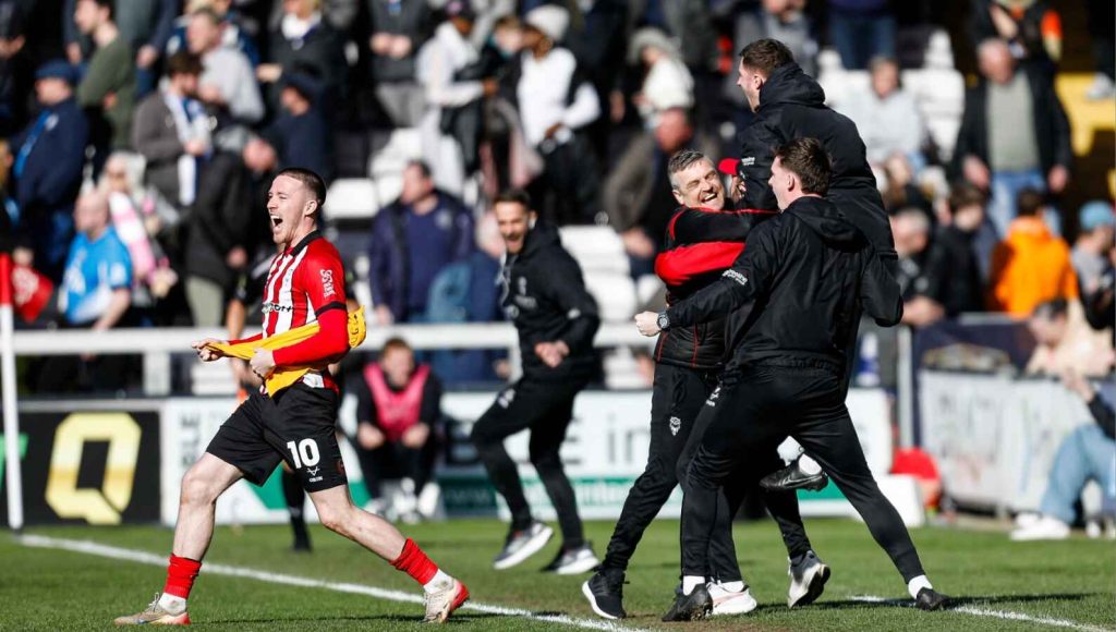 Lincoln City’s bench, and scorer Jack Moylan, celebrate