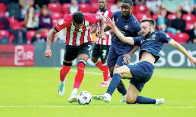 Wigan’s Morgan Fox, right, slides in to tackle Lincoln’s Reeco Hackett-Fairchild