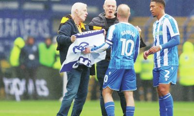 Sheffield Wednesday fans talk to Owls skipper Barry Bannan after invading the pitch to protest against owner Dejphon Chansiri