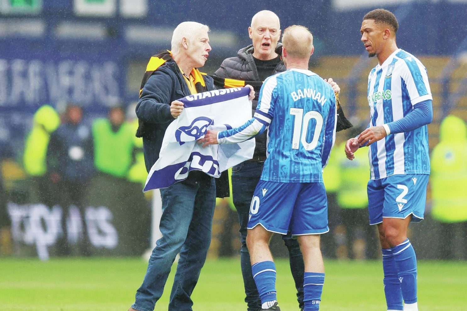 Sheffield Wednesday fans talk to Owls skipper Barry Bannan after invading the pitch to protest against owner Dejphon Chansiri