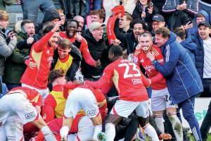 Elated Salford City players and fans celebrate Matt Butcher’s late winner