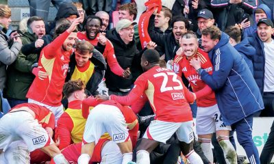 Elated Salford City players and fans celebrate Matt Butcher’s late winner